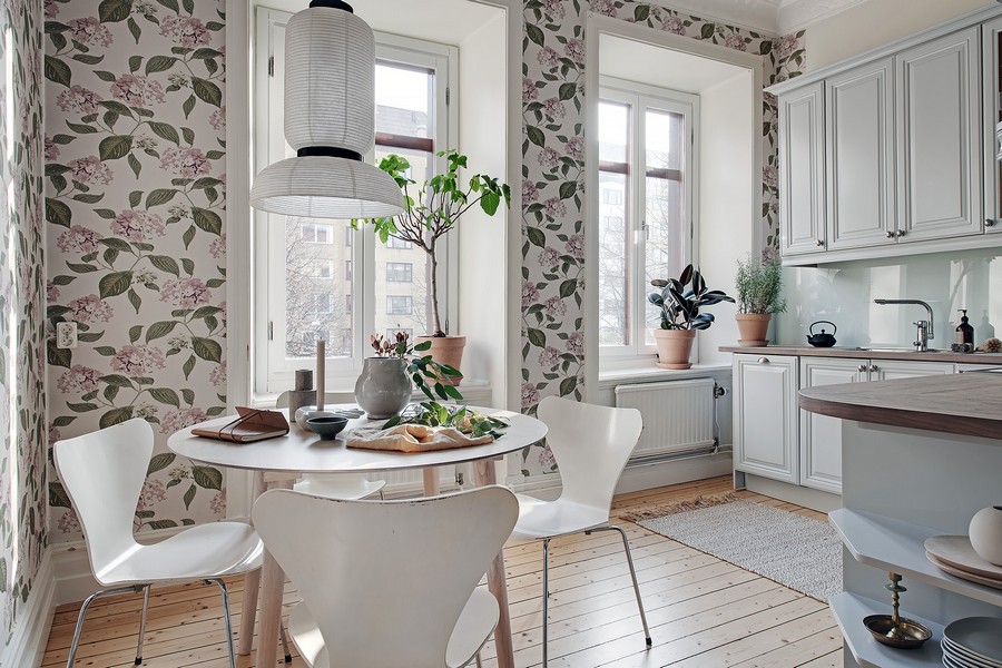 Green leaves on the wallpaper in the kitchen with white furniture