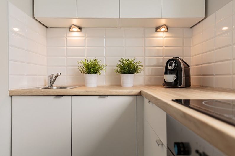 Små lamper under de hængende skabe i et kompakt køkken