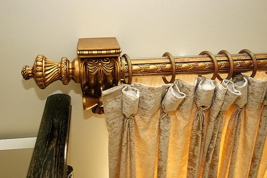 Curtain with rings on a gilded cornice in the kitchen