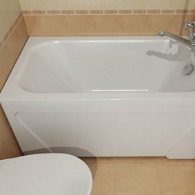 White bath on a background of beige tiles