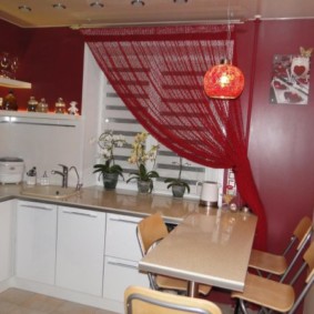 ผ้าม่านสีแดงบนหน้าต่างห้องครัวพร้อมเฟอร์นิเจอร์สีขาว